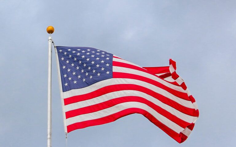 usa-flag-waving-on-white-metal-pole-1550342-scaled
